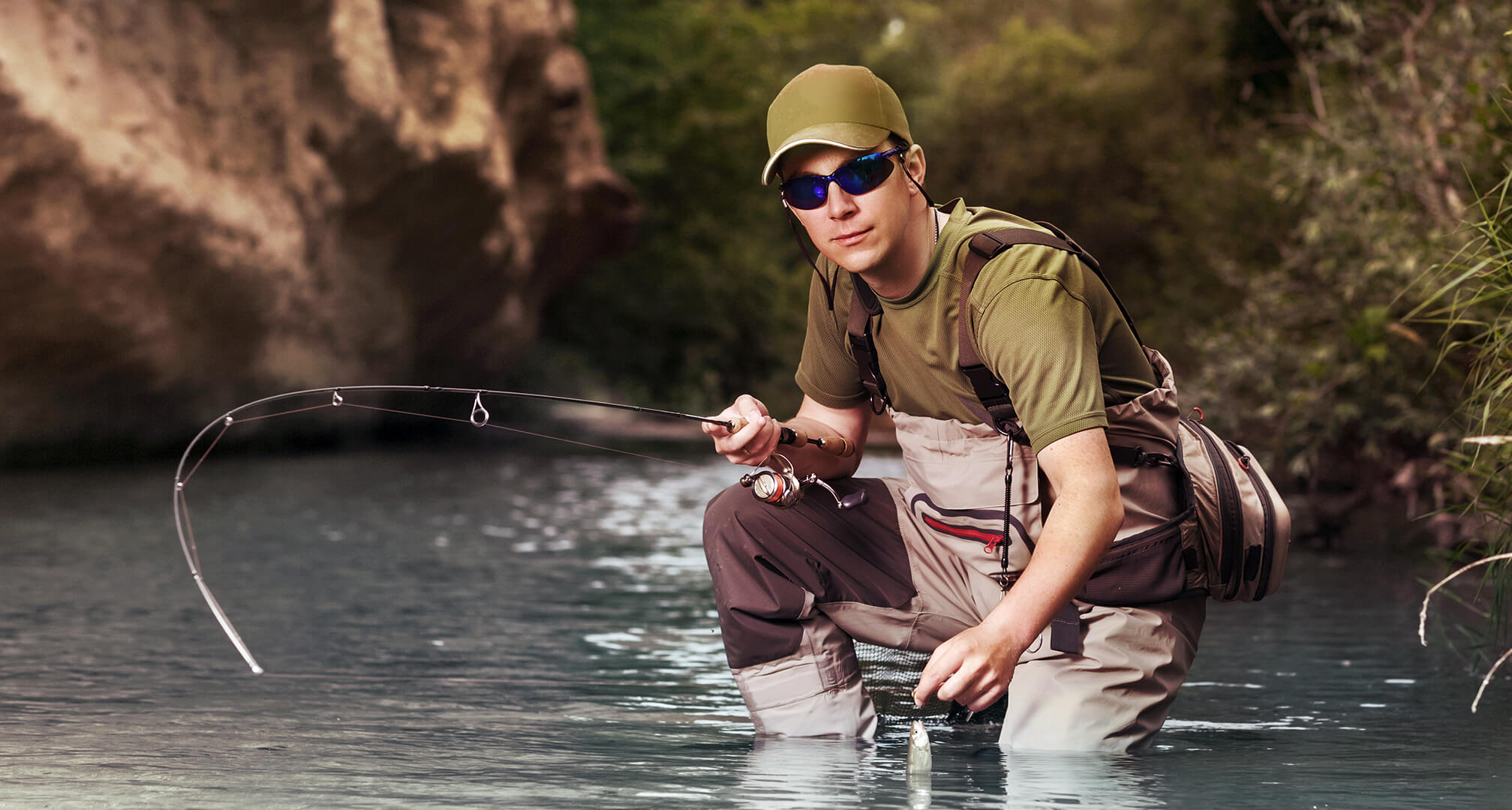 pescatore inginocchiato in acqua mentre indossa occhiali da sole