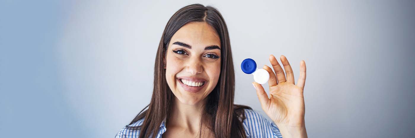 donna sorridente con in mano un astuccio per lenti a contatto