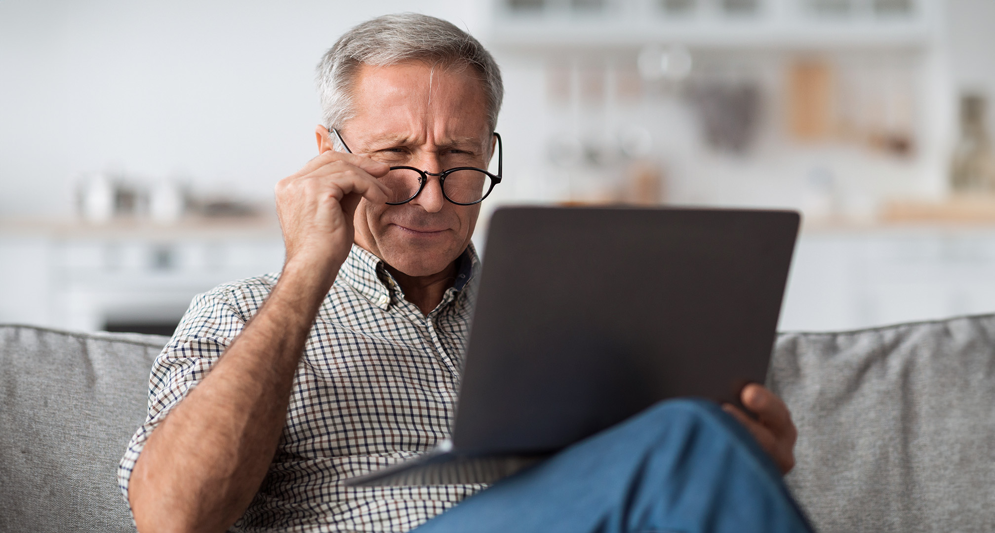 persona che indossa occhiali e strizza gli occhi davanti ad un computer portatile