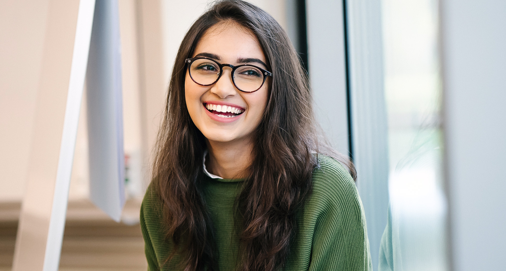 foto di una persona sorridente con i capelli lunghi che indossa occhiali neri