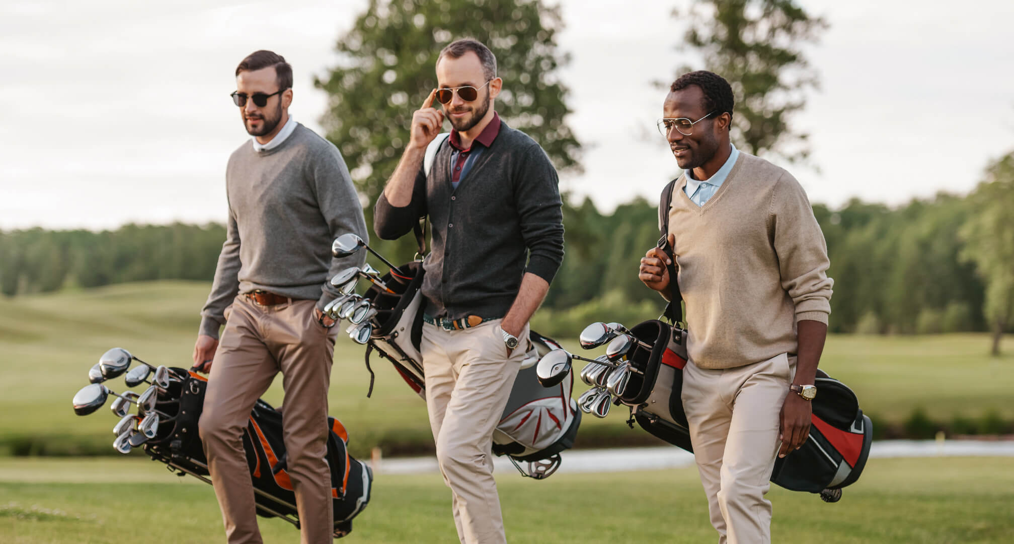 tre persone che giocano a golf con occhiali da sole e sacche da golf