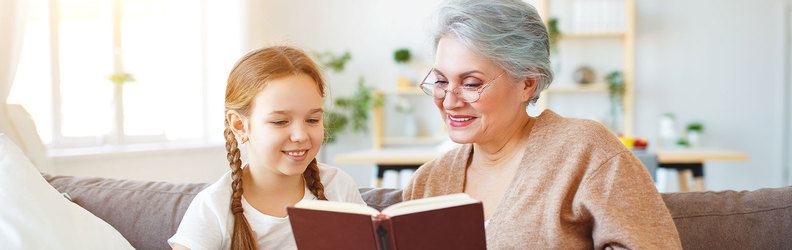 bambina e anziana che leggono un libro